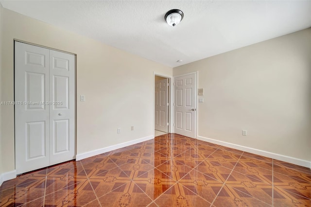 unfurnished bedroom featuring baseboards, a textured ceiling, and a closet