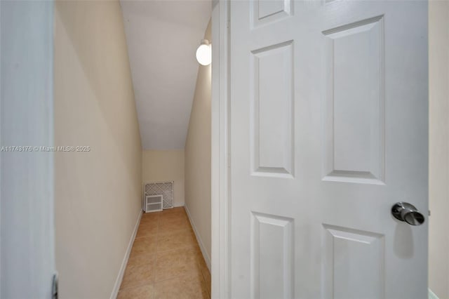 hall with lofted ceiling, light tile patterned flooring, visible vents, and baseboards