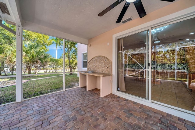 unfurnished sunroom with visible vents and a ceiling fan