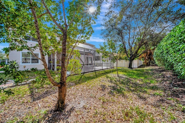 view of yard with a pool, fence, and glass enclosure
