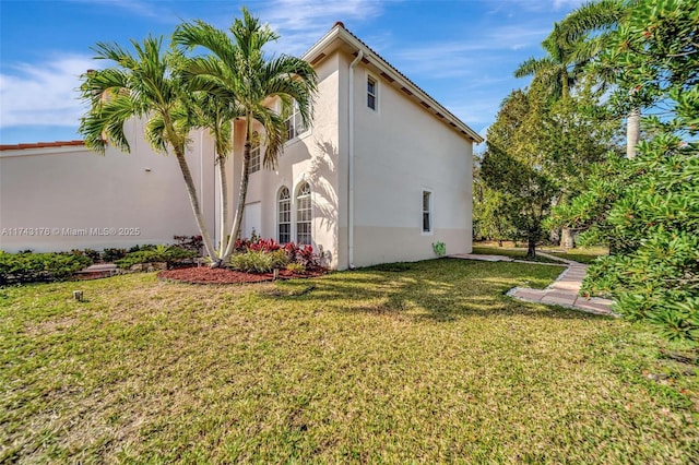 view of side of property with a lawn and stucco siding