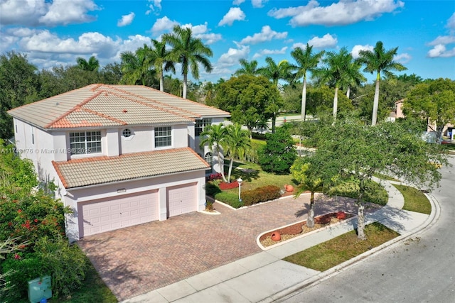 view of front facade featuring stucco siding, decorative driveway, an attached garage, and a tile roof