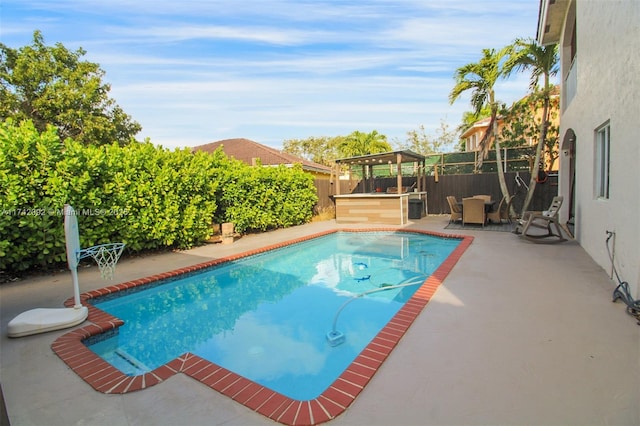 view of pool with a patio, a gazebo, and an outdoor bar