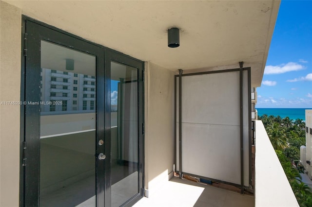 balcony with a water view and french doors