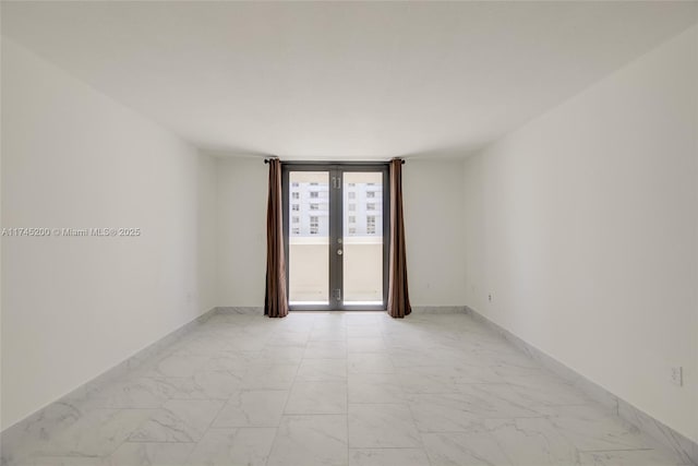 empty room featuring marble finish floor, french doors, and baseboards