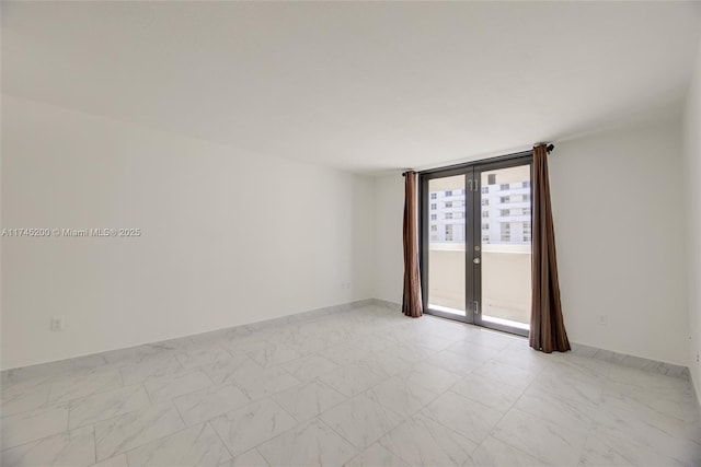 spare room with marble finish floor, french doors, and a wall of windows