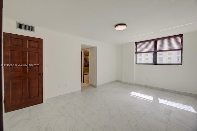 spare room with marble finish floor, baseboards, and visible vents