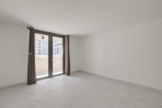 empty room featuring french doors, marble finish floor, and baseboards