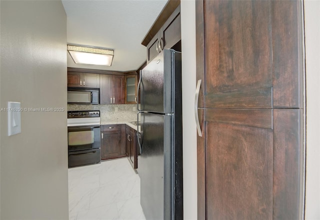 kitchen with marble finish floor, light countertops, backsplash, black appliances, and glass insert cabinets