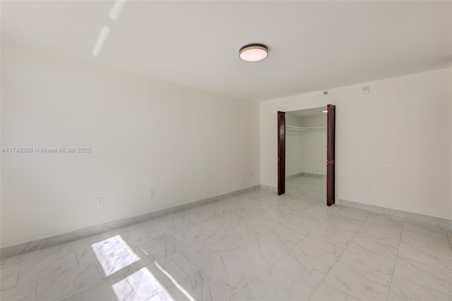 empty room featuring marble finish floor and baseboards