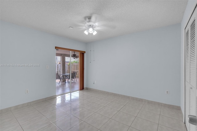 tiled empty room with ceiling fan and a textured ceiling