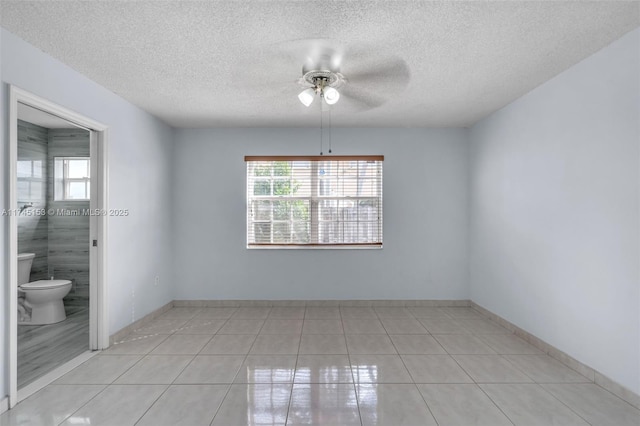 spare room featuring light tile patterned flooring, a healthy amount of sunlight, a textured ceiling, and ceiling fan