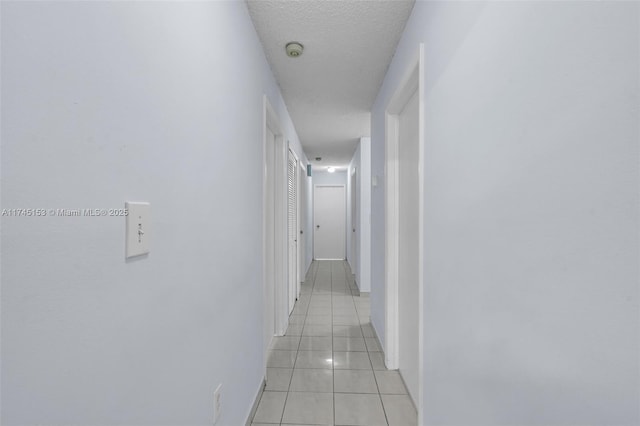 hall with light tile patterned flooring and a textured ceiling