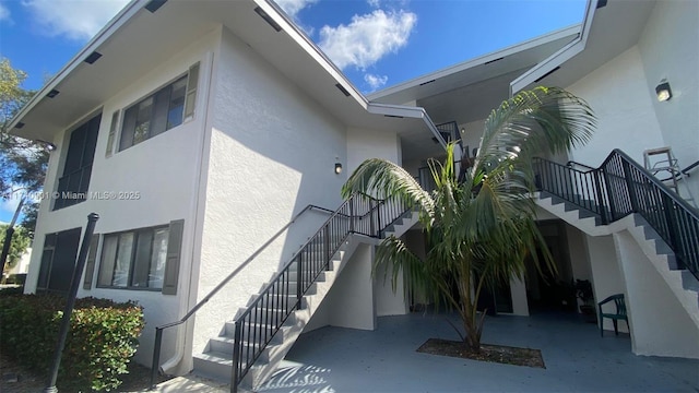 view of side of home featuring stairs and stucco siding