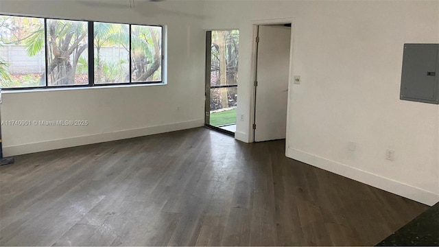 unfurnished room with dark wood-style floors, electric panel, and baseboards