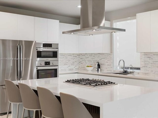 kitchen featuring stainless steel appliances, island exhaust hood, a breakfast bar area, and white cabinetry