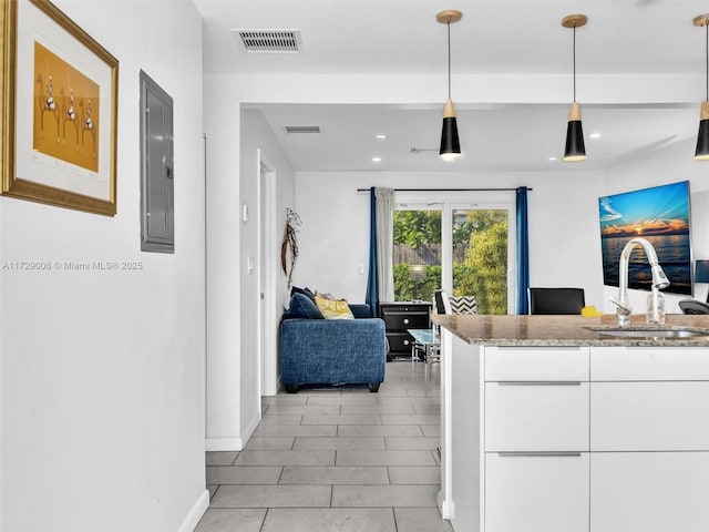 kitchen with decorative light fixtures, electric panel, sink, and white cabinets