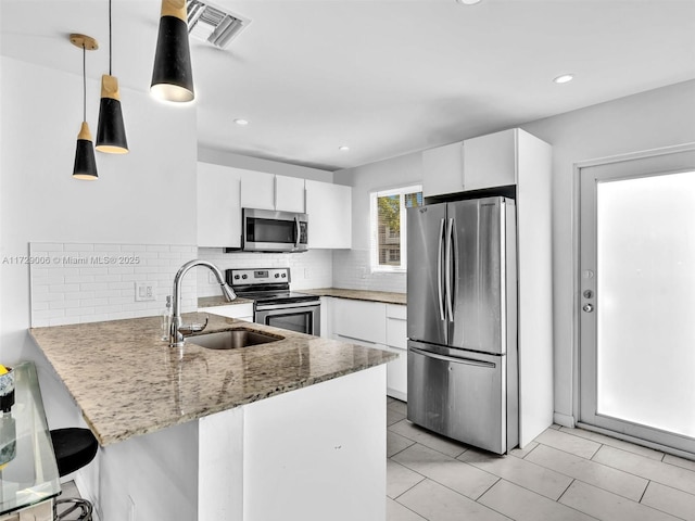 kitchen featuring white cabinetry, appliances with stainless steel finishes, decorative light fixtures, and kitchen peninsula