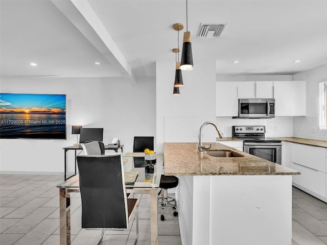 kitchen with sink, hanging light fixtures, stainless steel appliances, a kitchen breakfast bar, and white cabinets