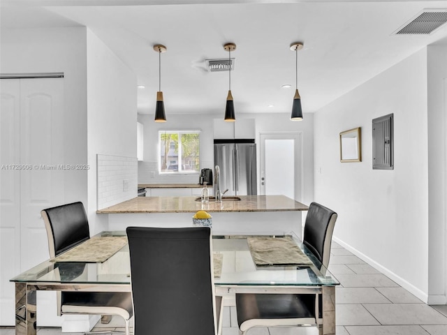 kitchen with pendant lighting, stainless steel fridge, electric panel, tasteful backsplash, and kitchen peninsula