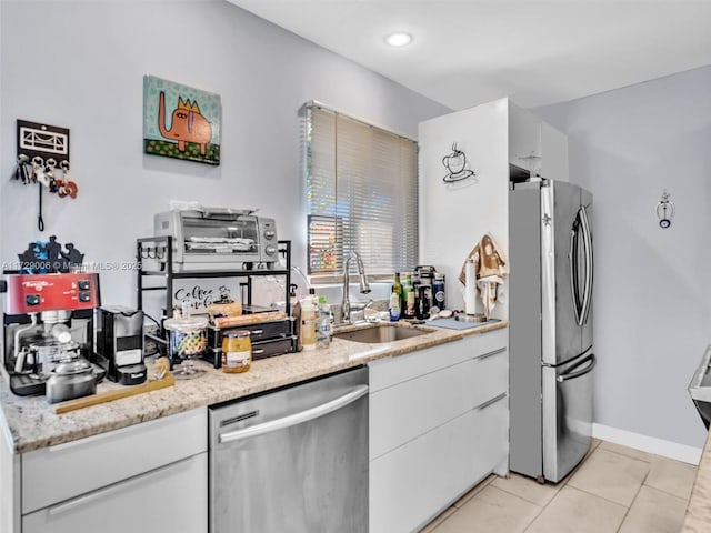 kitchen with white cabinetry, sink, light tile patterned floors, light stone counters, and stainless steel appliances