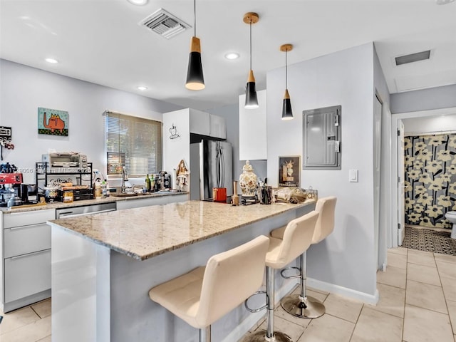 kitchen featuring appliances with stainless steel finishes, decorative light fixtures, a breakfast bar, and white cabinets