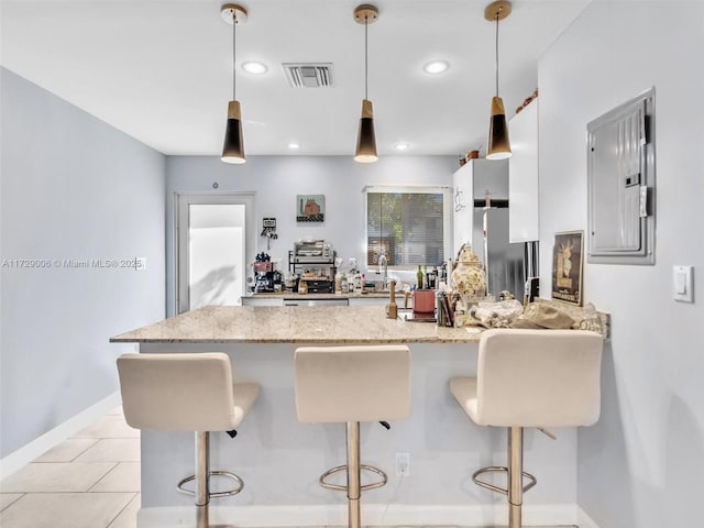 kitchen with pendant lighting, white cabinetry, a breakfast bar area, and electric panel