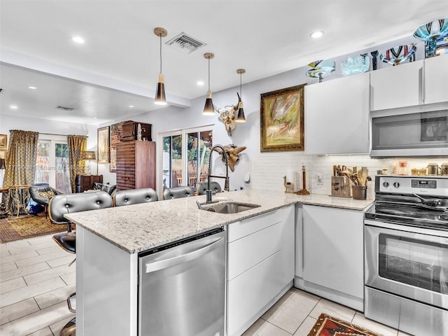 kitchen with appliances with stainless steel finishes, pendant lighting, white cabinetry, sink, and kitchen peninsula