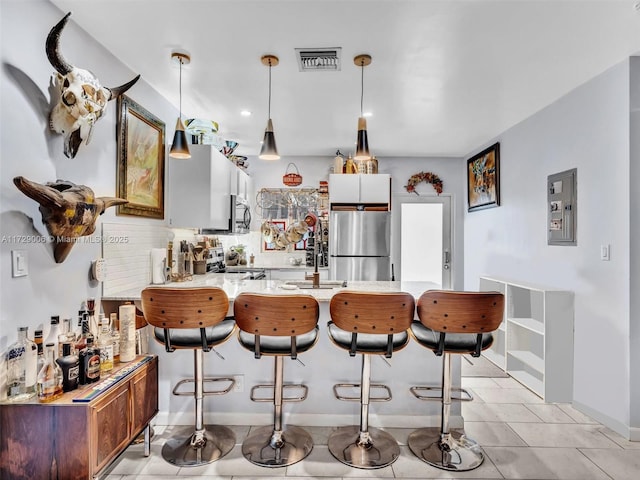 kitchen featuring pendant lighting, tasteful backsplash, electric panel, kitchen peninsula, and stainless steel appliances