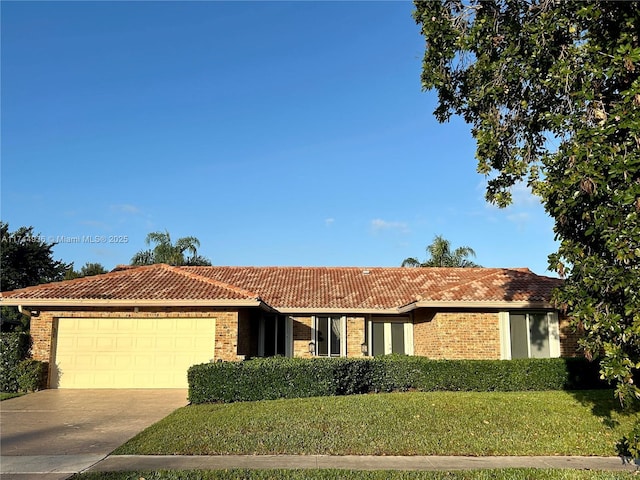 ranch-style home featuring a tiled roof, a front yard, driveway, and a garage