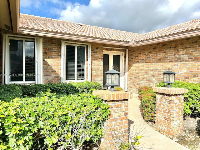 entrance to property with brick siding and a tile roof