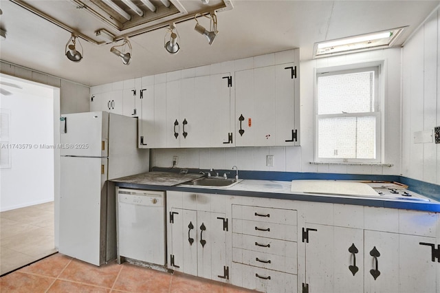 kitchen with light tile patterned floors, white appliances, sink, and white cabinets