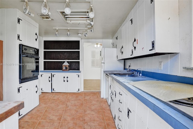 kitchen featuring light tile patterned flooring, sink, white cabinetry, white dishwasher, and oven