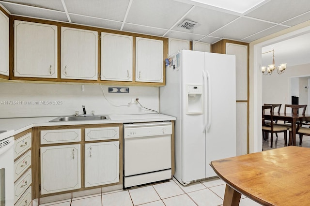 kitchen featuring sink, white appliances, light tile patterned floors, a drop ceiling, and decorative light fixtures