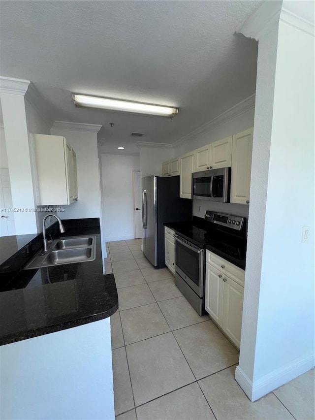 kitchen with sink, light tile patterned floors, appliances with stainless steel finishes, white cabinetry, and ornamental molding