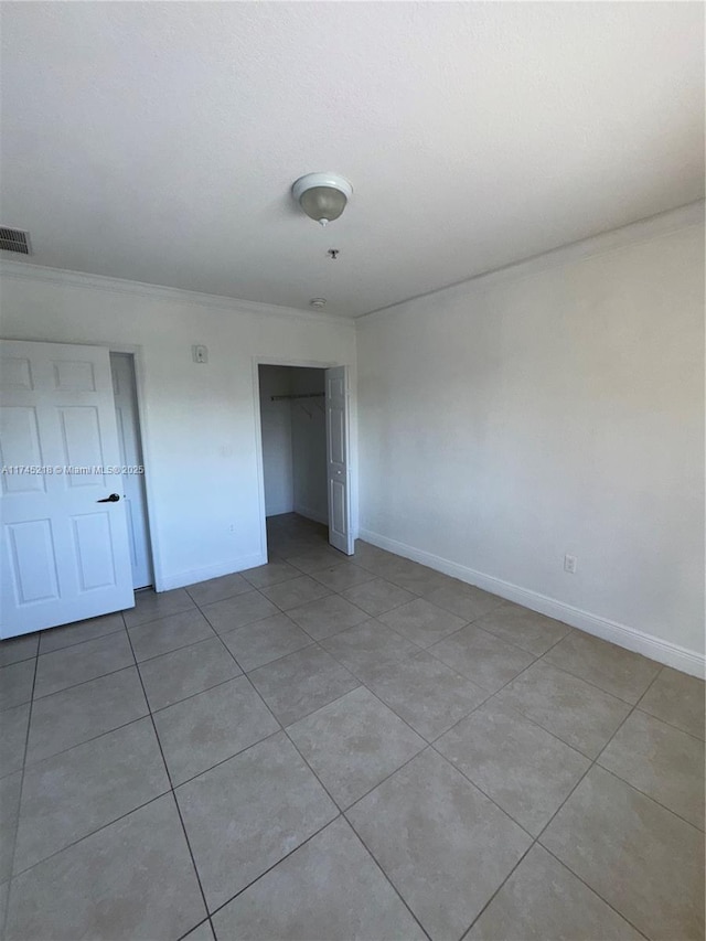 unfurnished bedroom featuring light tile patterned floors, crown molding, and a closet