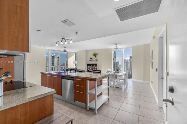 kitchen featuring stainless steel dishwasher, light tile patterned floors, an island with sink, and ceiling fan