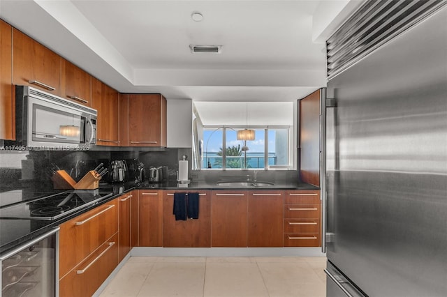 kitchen featuring light tile patterned floors, sink, dark stone countertops, stainless steel appliances, and tasteful backsplash