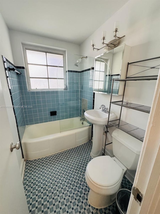 full bathroom featuring a healthy amount of sunlight, toilet, tiled shower / bath combo, and sink