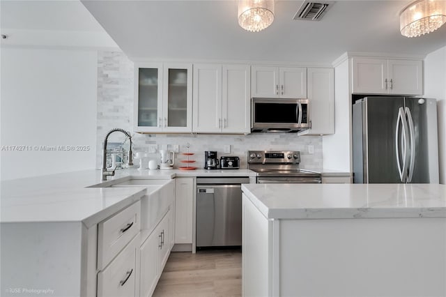 kitchen featuring sink, stainless steel appliances, light stone counters, tasteful backsplash, and white cabinets