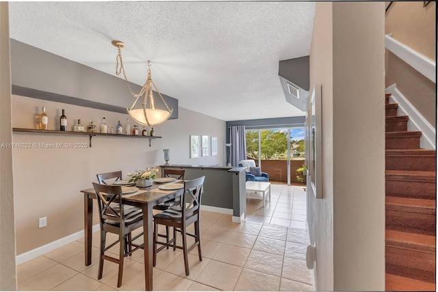 tiled dining space featuring vaulted ceiling and a textured ceiling