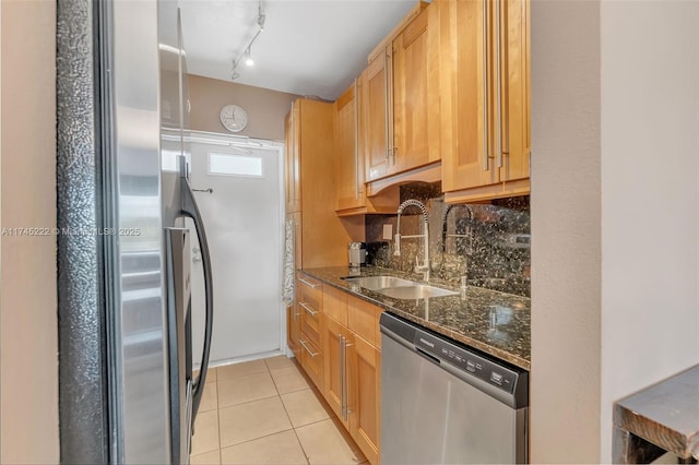 kitchen featuring sink, decorative backsplash, dark stone counters, light tile patterned floors, and stainless steel appliances