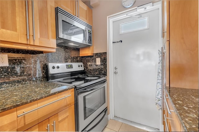 kitchen featuring tasteful backsplash, stainless steel appliances, light tile patterned floors, and dark stone counters