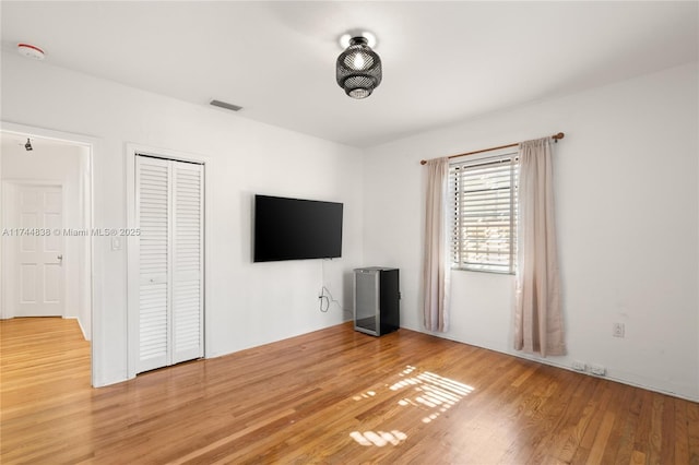 unfurnished living room featuring wood finished floors and visible vents