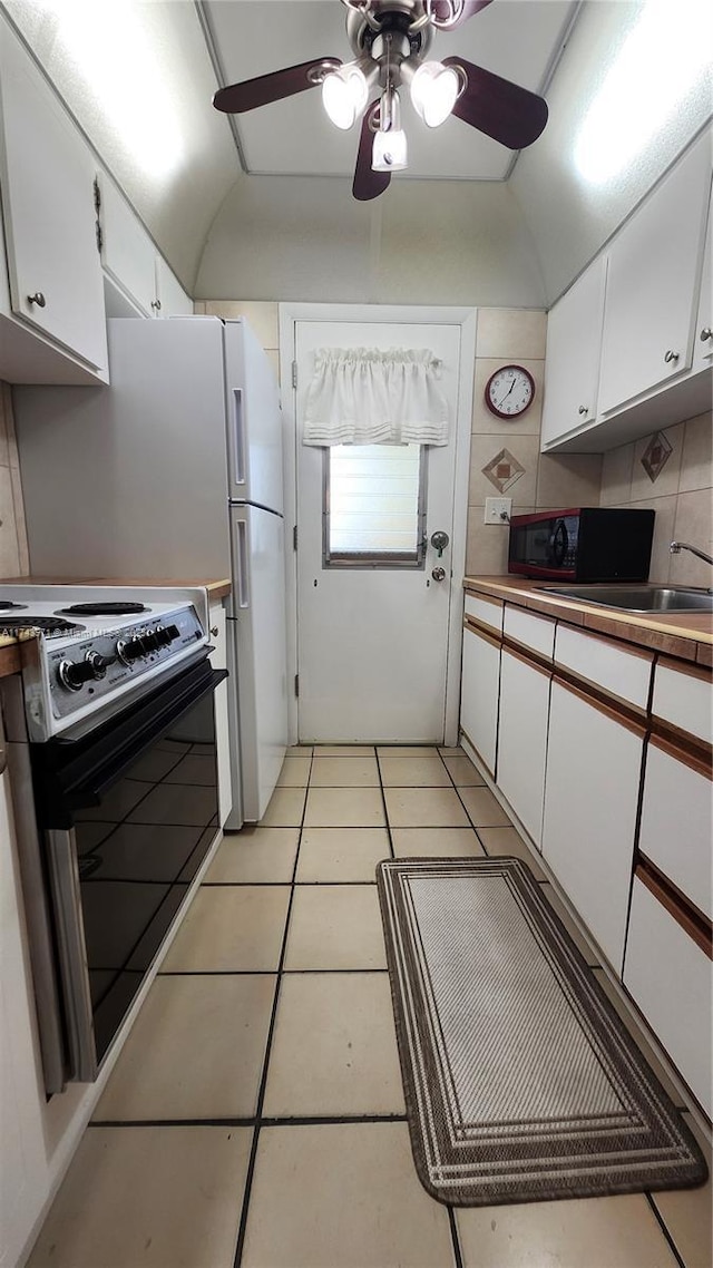 kitchen featuring electric stove, white cabinets, black microwave, and light tile patterned floors