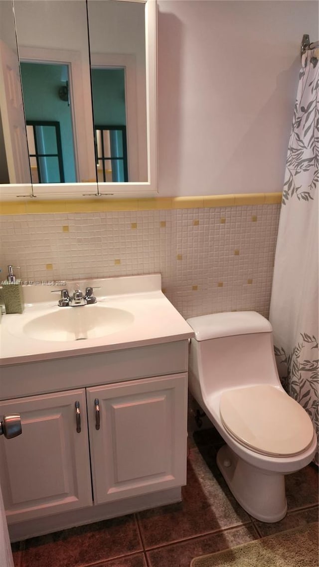 full bathroom with wainscoting, toilet, tile patterned floors, vanity, and tile walls