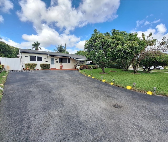 single story home featuring driveway, a front yard, and fence