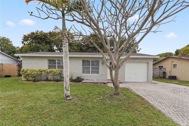 ranch-style home with a garage, a front yard, and central air condition unit