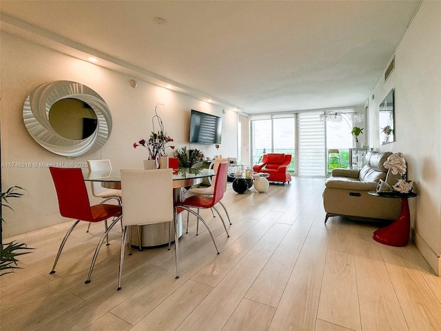 dining room with light wood-type flooring, visible vents, and expansive windows