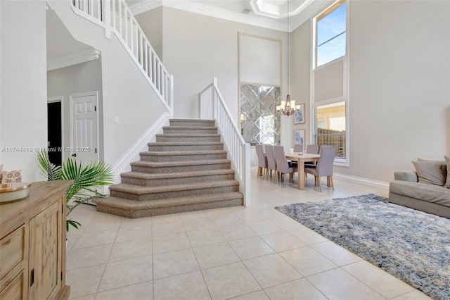 entrance foyer with light tile patterned floors, a towering ceiling, stairway, crown molding, and a notable chandelier